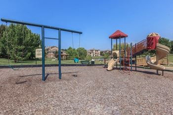 A playground with slides and swings at Stonepost Lakeside Apartments in Olathe, KS.